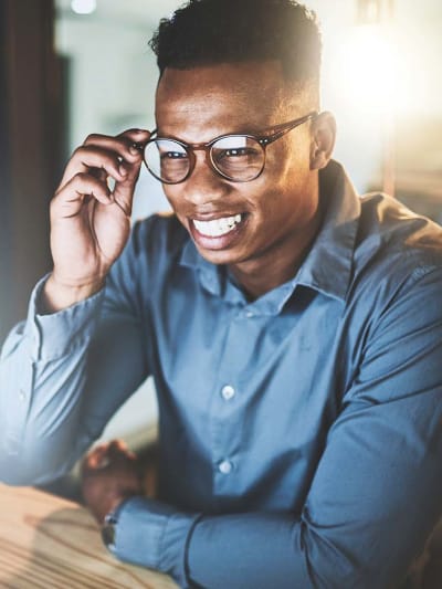 An employee at their desk in an office setting, smiling at their desktop monitor as if talking on a video call.