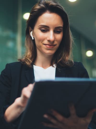 A woman with short hair smiling and holding a tablet.