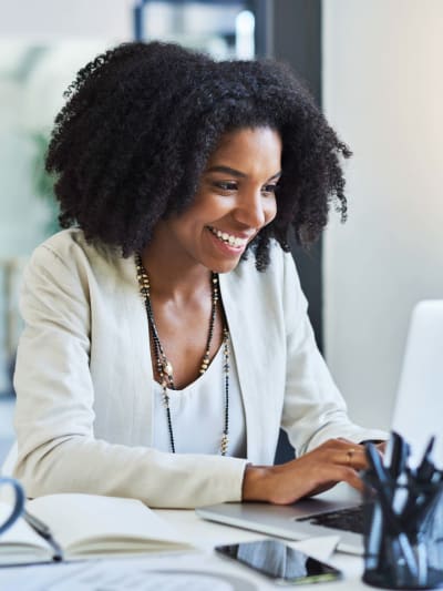 Person smiles while working at a white laptop.