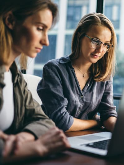 Two female colleagues looking at a laptop