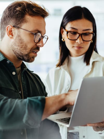 Coworkers discuss what they see on a laptop