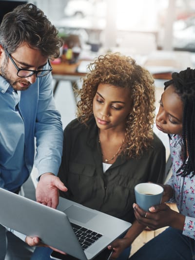 Three technology professionals looking at a laptop