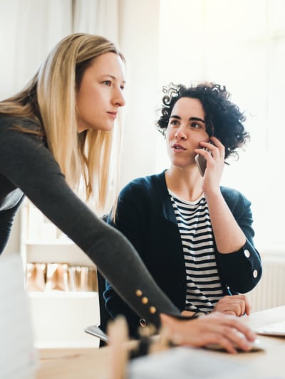 Two female colleagues at a desk talking