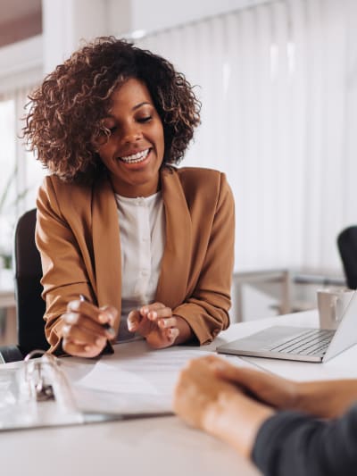 Two people discussing an insurance policy while sitting at a desk in a meeting room.