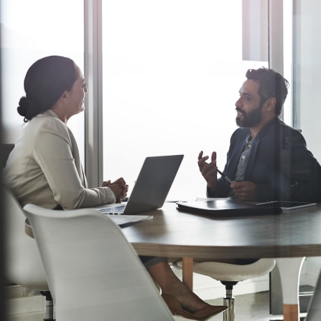 Two people discuss business in an office conference room.