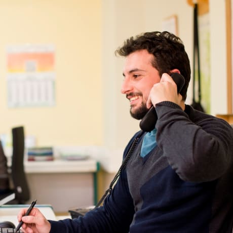 Person sits at a desk with a stylus and cell phone.