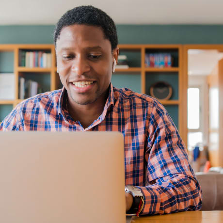A person smiles while participating in a free, virtual cloud consultation on a laptop at home.