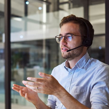 A managed services expert sits at a desk with a headset and collaborates virtually with a customer.