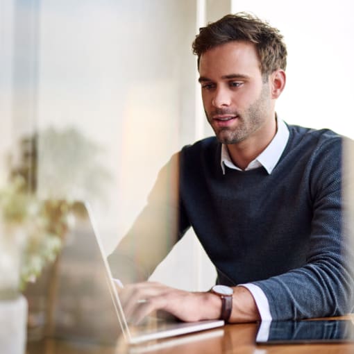 A person sits at a laptop computer in an office.