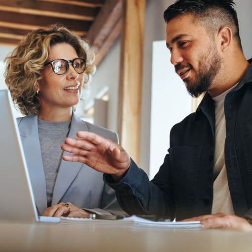 Two people discuss business in front of a laptop.