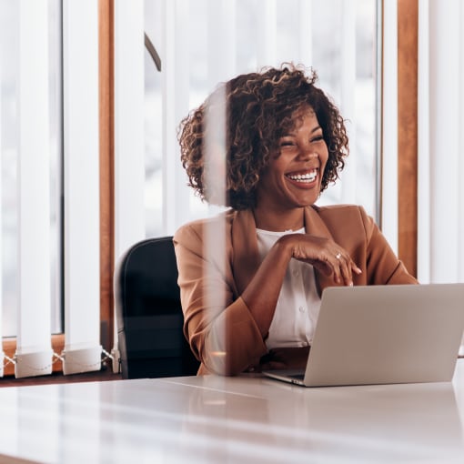 Person sits in office conference room in front of laptop.