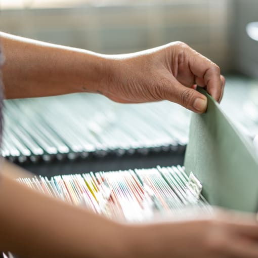 Person pulls a file from a large filing cabinet.