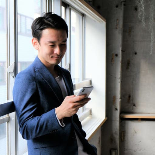 Person leans against window holding a cell phone.