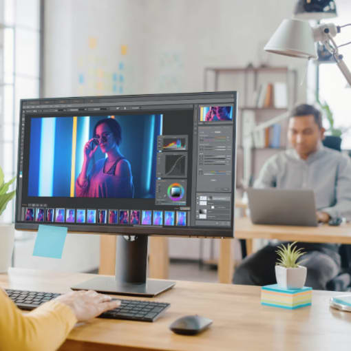 Graphic designer works on a computer in an open office setting.