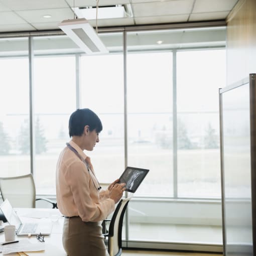 Person in a conference room with tall windows uses a tablet computer.