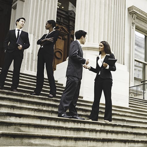 Four people stand on the stairs of a government building.