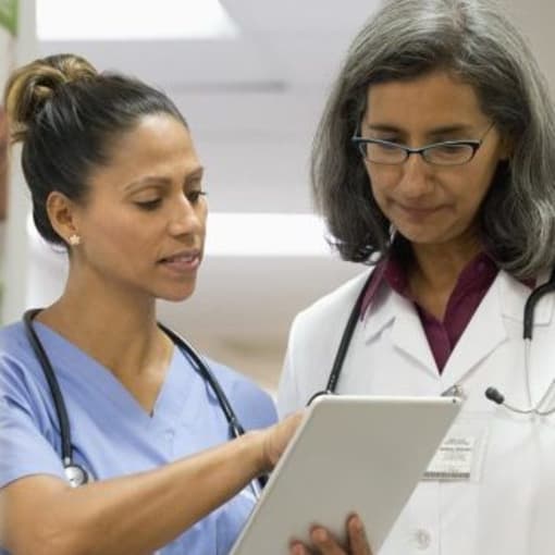 Two medical professionals discuss findings on a tablet computer.