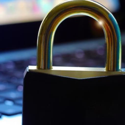 A lock stands in front of a laptop keyboard.