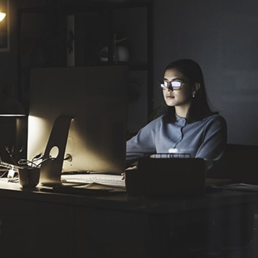 Person sits in a dark office working on their computer.