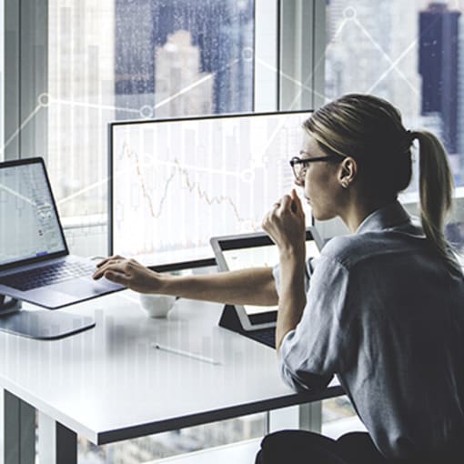 Person sits in their office in front of computer overlooking a cityscape.