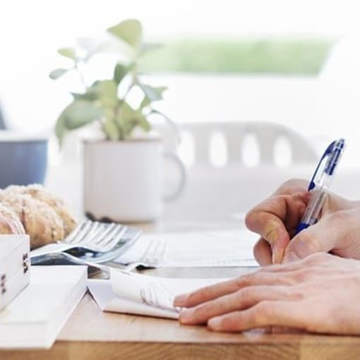 Person uses pen to write on paper documents.