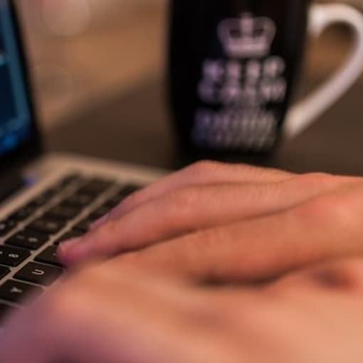 Close-up of hands coding on a laptop.