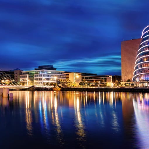 Cityscape illuminated on a river at dusk.