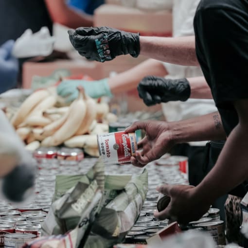 People wearing gloves inspect food (cans, fruit, etc.).