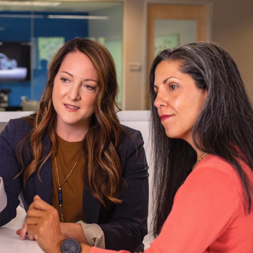 Two people sit at a computer and discuss findings.