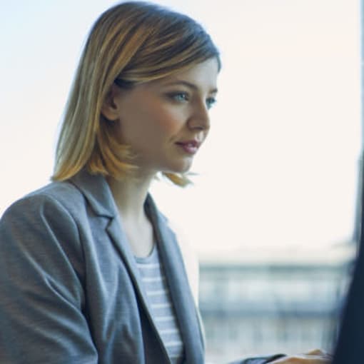 Person sits in their office in front of computer monitors.