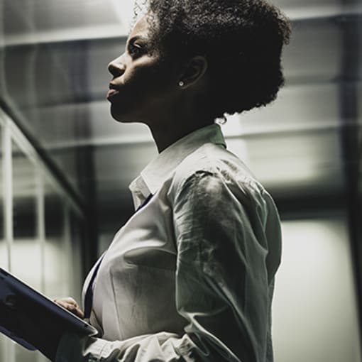 Person holding tablet computer stands in a datacenter.