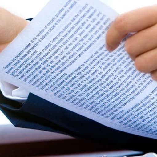 Close-up photo of two people holding pens and holding paper forms and documentation.