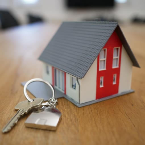 A small model of a house sits near house keys.