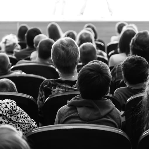 Black-and-white photo of young students in an auditorium.