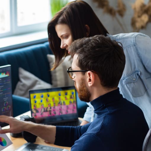 Two people discuss digital assets on a desktop computer.