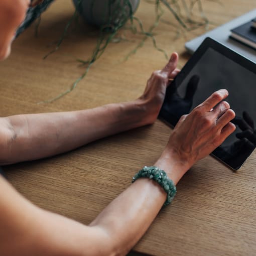 Person at a desk uses a tablet computer.