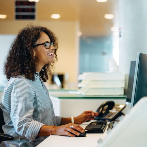 Person in glasses at a desk in an office works at a computer.