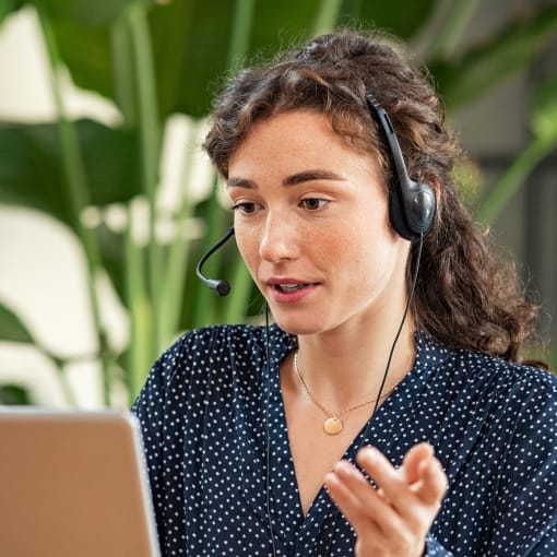 Person wearing a headset talks to someone through their laptop.