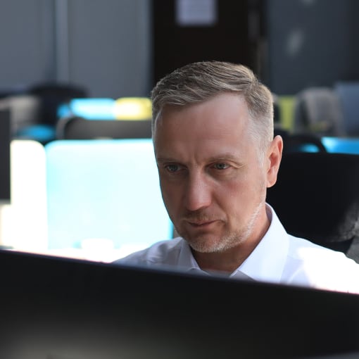 Person in white button-down shirt sits at a computer.