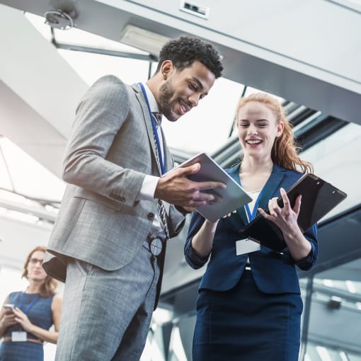 Business people look at tablet computers in a modern steel and glass office.