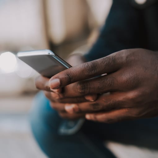 Close-up of a person sitting and holding a cell phone.