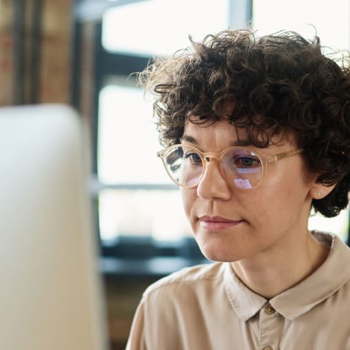 Person with curly hair and a collared shirt sits in front of a computer monitor.