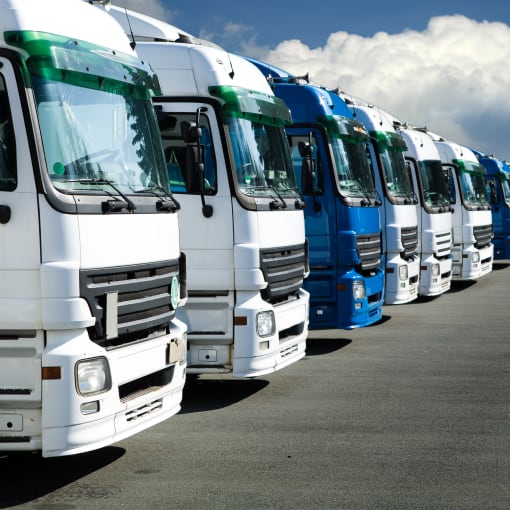 Fleet of large trucks in a parking lot.