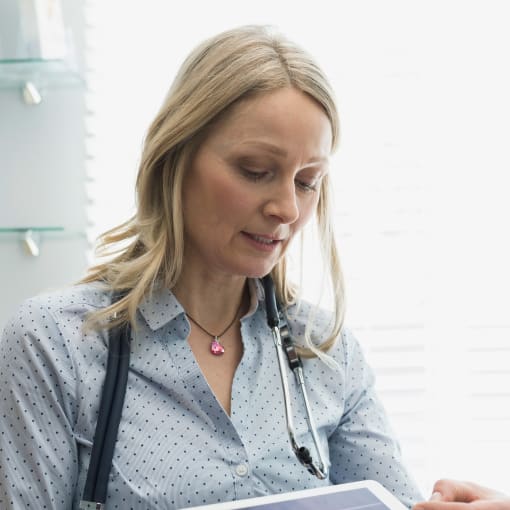 Clinician holding a digital tablet pointing to a medical image.