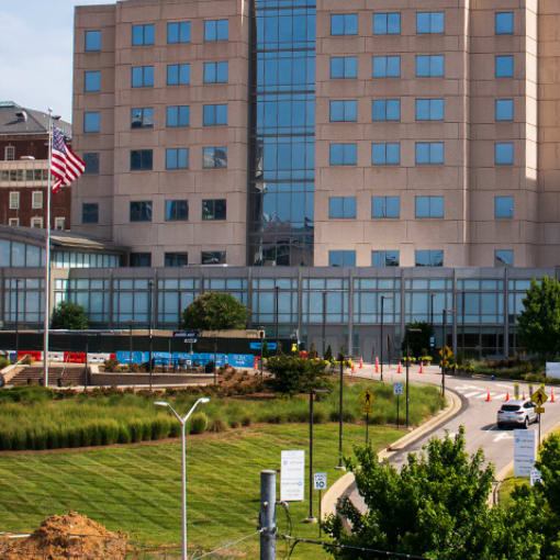 Exterior shot of a multistory glass and brick building with an American flag in front. 