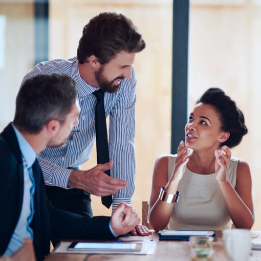 Three professionals holding work discussion in an office.