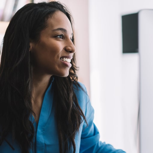 Smiling person with hands on the keyboard of a desktop computer.