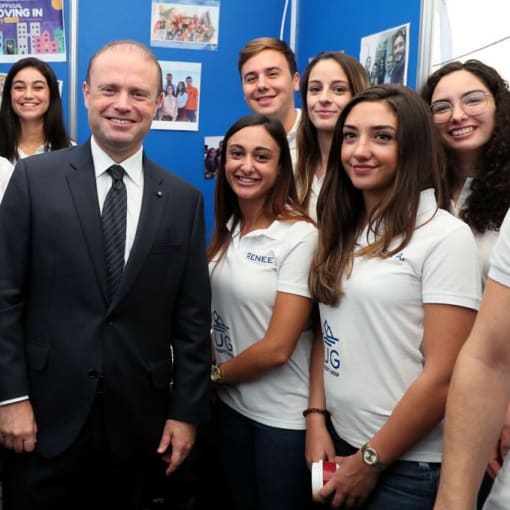 Group of people, some in T-shirts and others in suits, stand together and smile for the camera.