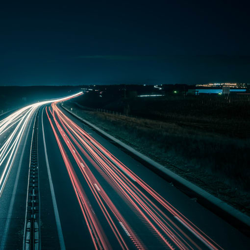 Time-lapse photo of cars on a highway at night.