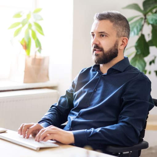 Person sits in a bright office, working on a desktop computer.